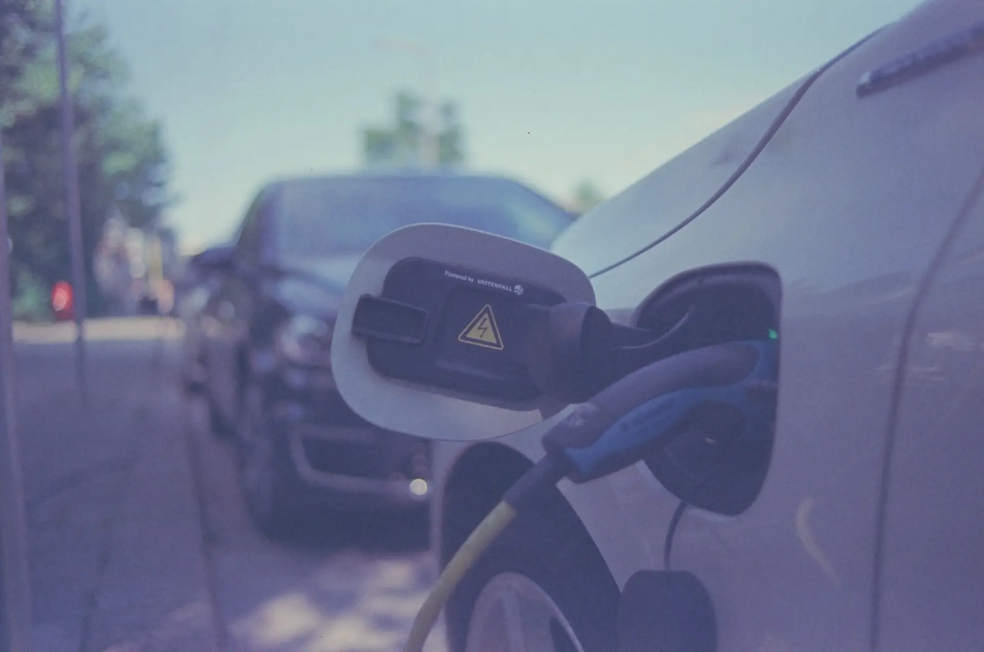 Electric vehicle charging cable plugged into a car in a parking bay