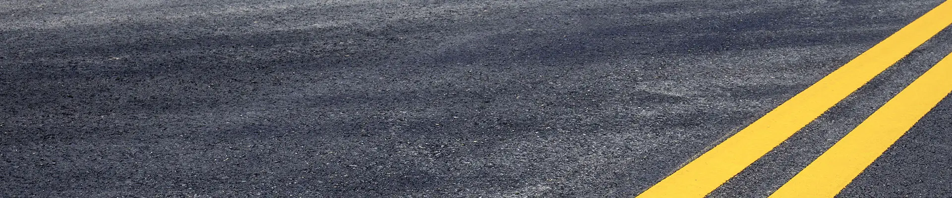 Yellow road markings painted on asphalt pavement